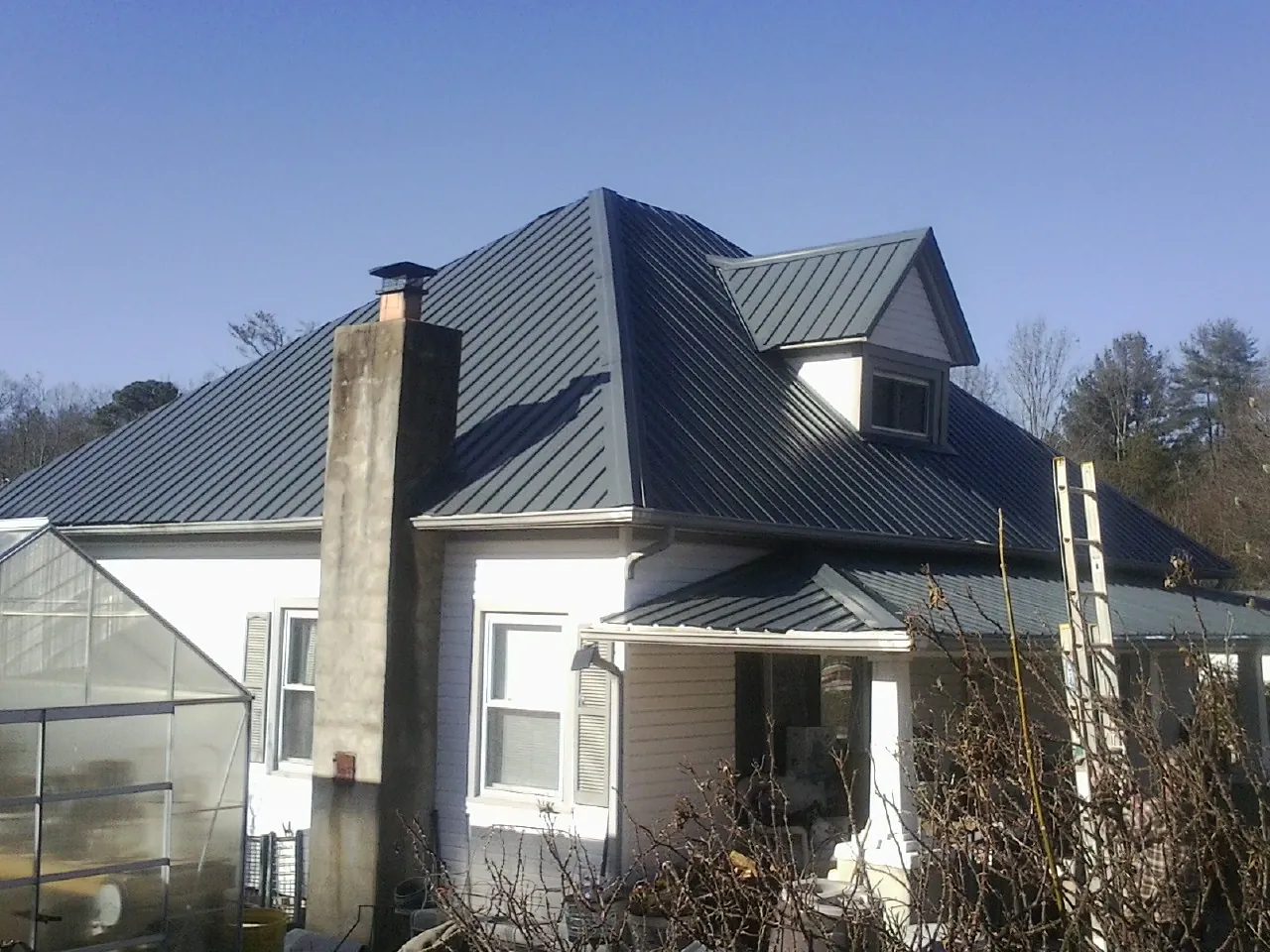 Dark blue standing seam metal roof on a white farmhouse with dormer — Slate & Tile Roof Repair by Roofing Brothers in Saint Meinrad