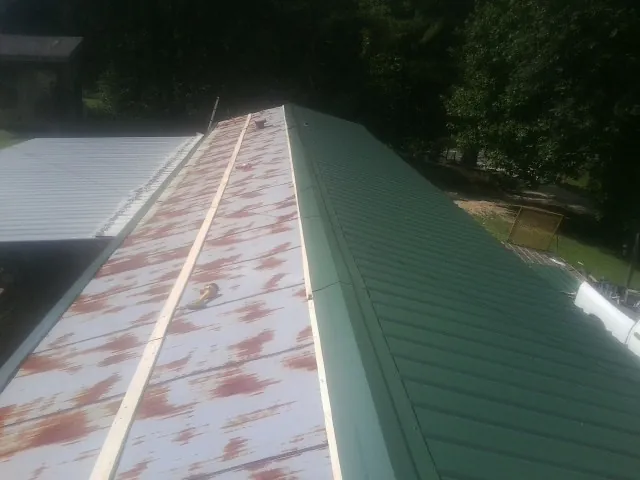 Old rusted panels beside newly installed green metal roofing — Wind Damage Roof Repair by Roofing Brothers in Saint Meinrad