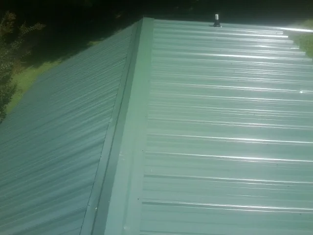 New green metal panels meeting at the ridge of a roof — Flat Roof Repair work by our crew in Saint Meinrad