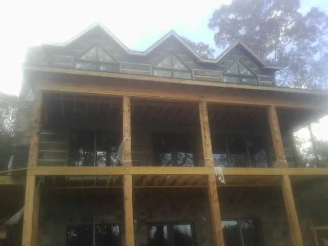Dormers and porch framing on a large log home under construction — Roof Coating work by our crew in Saint Meinrad