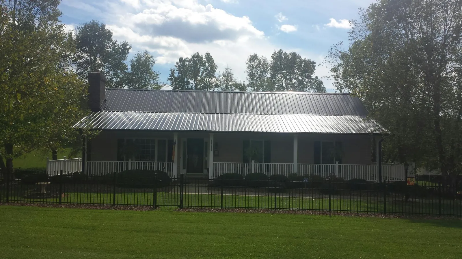 Gray metal roof on a brick ranch with a full width front porch — Gutter Guard Installation work by our crew in Saint Meinrad