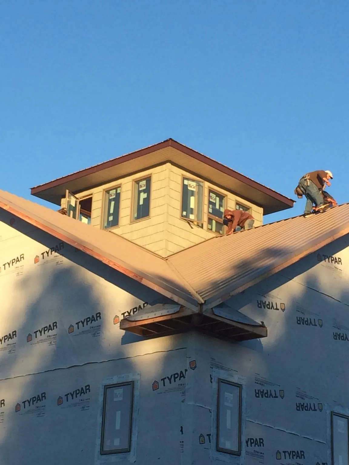 Roofers working around a rooftop cupola on a new metal roof at sunset — Roof Waterproofing in Saint Meinrad by Roofing Brothers